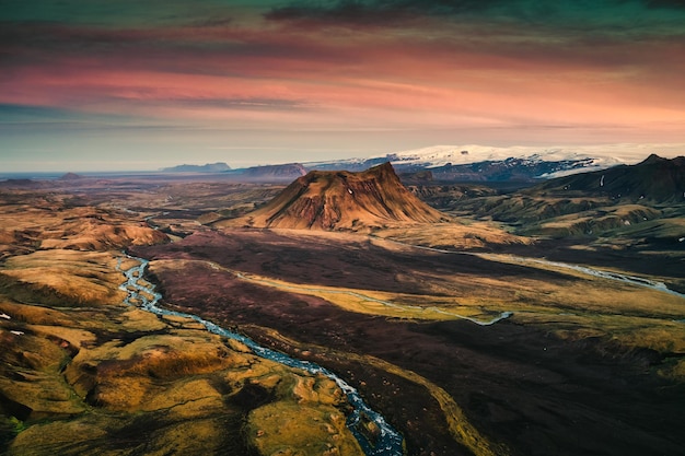 Cráter volcánico extinto entre el campo de lava y el río que fluye al atardecer en las Tierras Altas de Islandia en verano