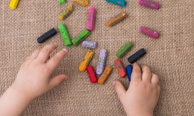 Foto crayones de colores usados y la mano de un niño pequeño sosteniendo uno