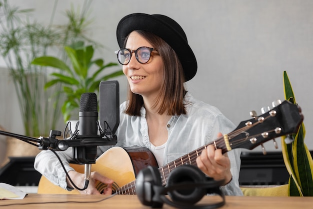 Creación de contenido de audio de música de podcast hermosa mujer europea podcaster en un sombrero con una guitarra o