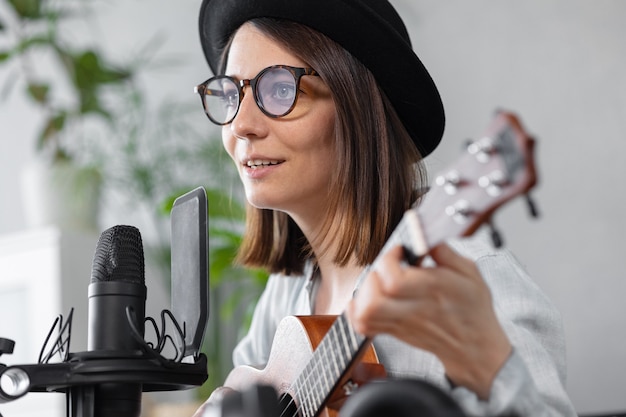 Creación de contenido de audio de música de podcast hermosa mujer europea podcaster en un sombrero con una guitarra o