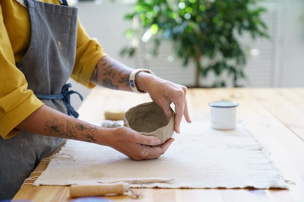 Creación de una mesa de cerámica en el estudio de cerámica con manos maestras que dan forma a una olla de barro mujer potter esculpir