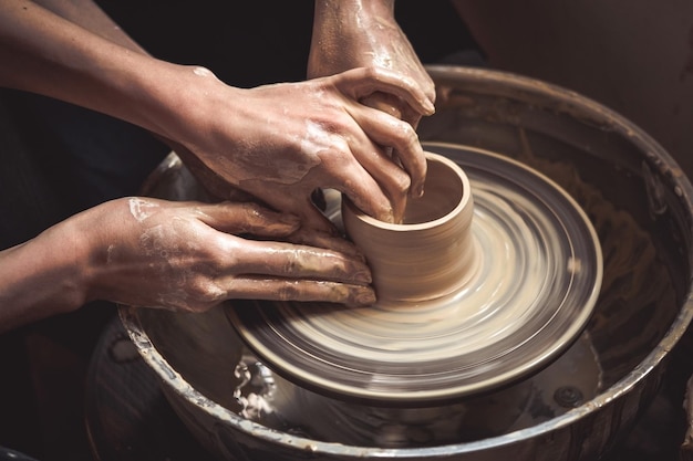 Creación de primer plano de jarrón de arcilla blanca. Maestro vasija El escultor en el taller hace una jarra de primer plano de loza. Torno de alfarero retorcido. Manos de hombre haciendo macro de jarra de arcilla.