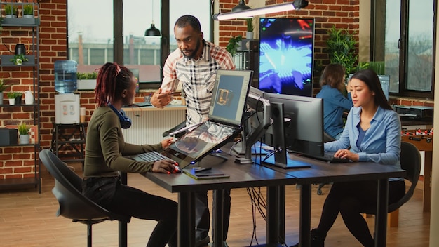 Creadores de contenido creativo que trabajan con la industria del desarrollo artístico, utilizando múltiples monitores en el escritorio. Equipo de empleados del departamento de producción que desarrollan tecnología de inteligencia artificial.