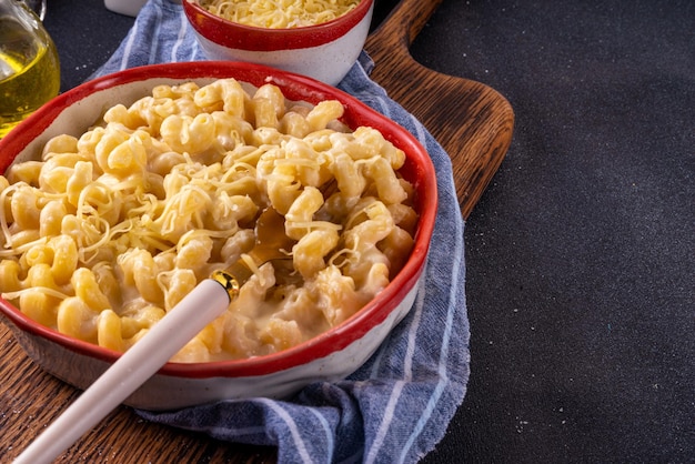 Creamy Mac und Käse mit Zutaten zum Kochen Macaroni-Pasta Bechamel-Creme-Sauce Milchkäse für die Herstellung von Mac- und Käse auf einem weißen Küchentisch aus Marmor