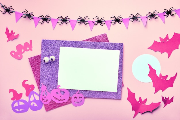 Creativa mesa plana de Halloween en papel rosa con espacio de copia. Tarjeta en blanco y decoraciones de papel: murciélagos y linterna