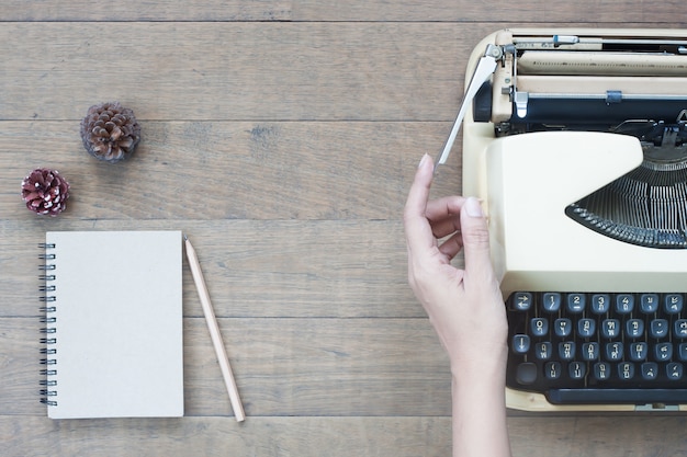 Foto creativa plana lay of vintage escritorio de trabajo con la mujer manos en la máquina de escribir, escritorio de textura de madera