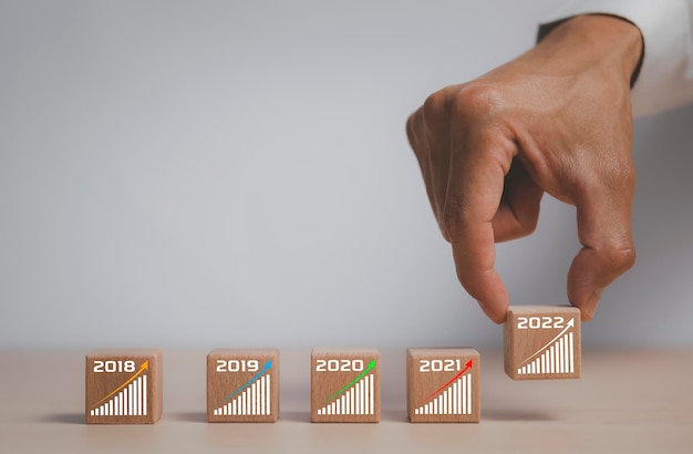 Crecimiento del concepto de negocio Proceso de éxito de 2022 años, empresario organizando a mano el apilamiento de bloques de madera como primer plano de la escalera, símbolo de crecimiento del gráfico de flecha, negocio del ciclo conceptual hacia arriba o hacia abajo,