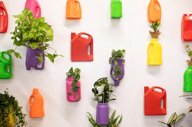 Crecimiento de plantas y flores verdes en macetas recicladas hechas de botellas y botes de plástico usados