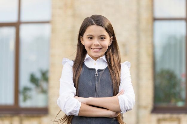 Cree en ti mismo. Niño seguro de mantener los brazos cruzados al aire libre. Mirada confiada de pupila. Tendencia de moda de regreso a la escuela. Educación primaria. El conocimiento aumenta la confianza.