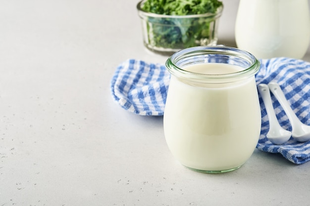 Foto crema agria o yogur natural en un frasco de vidrio con cucharas, concepto de salud y dieta