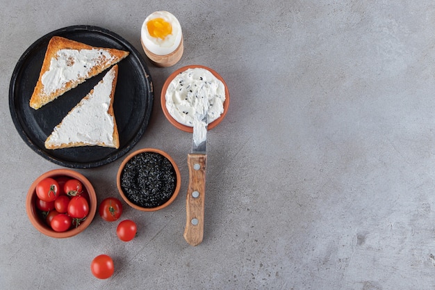 Crema agria, tomates cherry y pan tostado en la mesa de piedra.