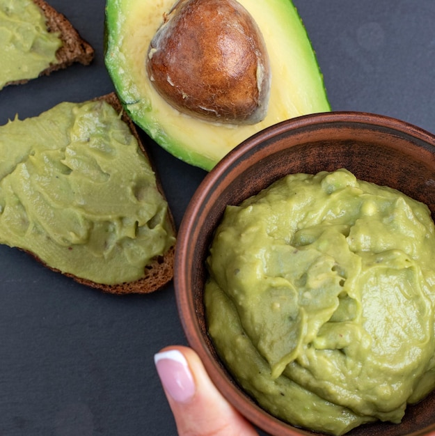 Crema de aguacate fresco en tazón de madera con rebanadas de pan placa de piedra negra de ion Vista superior