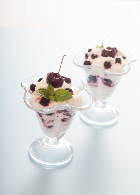 Crema batida con cerezas, grosellas y hojas de menta en cuencos de vidrio