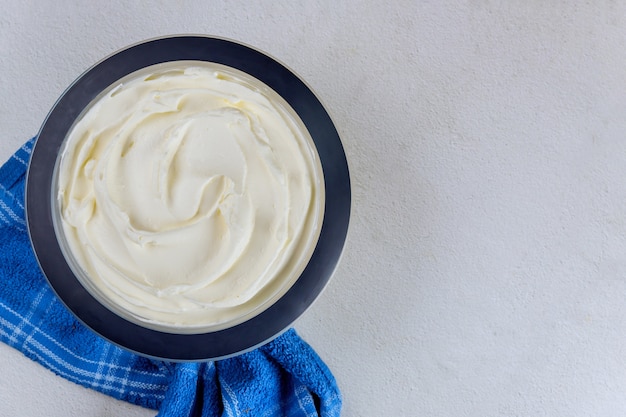 Foto crema batida de vainilla casera en un recipiente con toalla azul. vista superior.