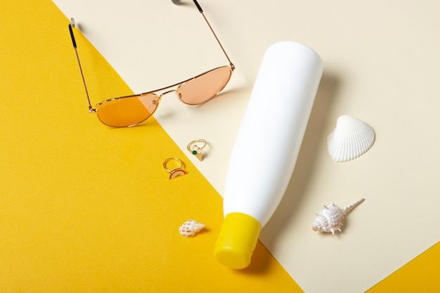 Foto crema para bebés y gafas de sol sobre un fondo amarillo accesorios para niñas pequeñas endecha plana