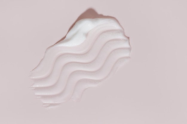 Crema de belleza blanca mancha en fondo rosado crema facial loción para el cuerpo muestra de deslizamiento