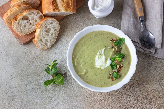 Crema de brócoli servida con menta, nata, semillas y pan. Concepto de comida vegetariana saludable.