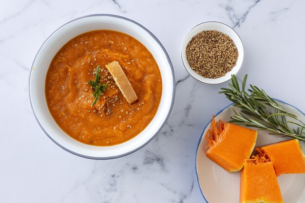 Crema de calabaza casera y saludable con pan desde arriba sobre mesa de mármol. Endecha plana