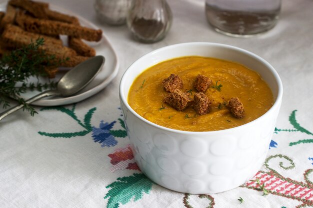 Crema de calabaza o zanahoria con picatostes y tomillo sobre madera