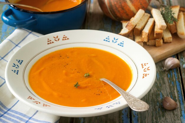 Foto crema de calabaza en un plato blanco sobre una mesa de madera