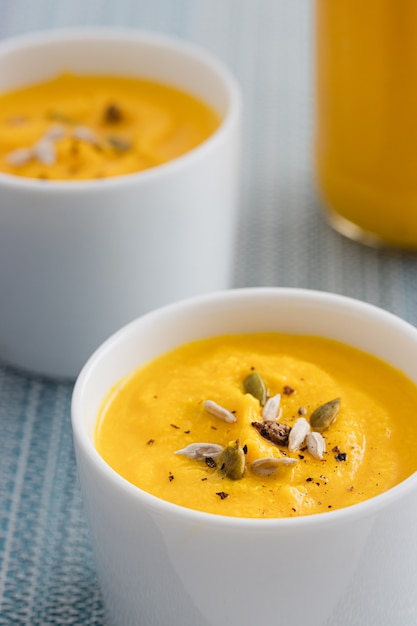 Crema de calabaza con semillas en dos tazones blancos