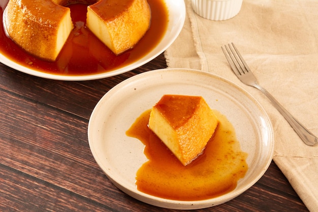 Crema caramelo leche condensada rebanada de pudín en vista delantera con fondo de madera