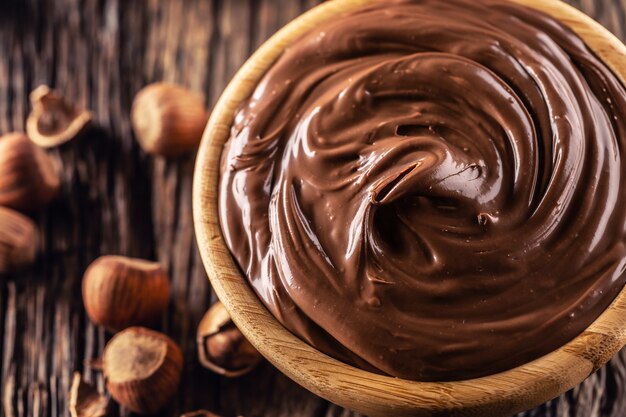 Foto crema de chocolate y avellanas en un tazón de madera - cierre.