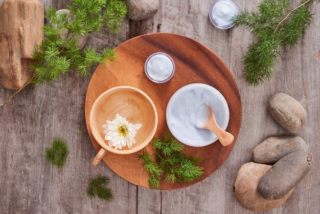 Crema cosmética y hojas frescas sobre fondo de mesa de madera