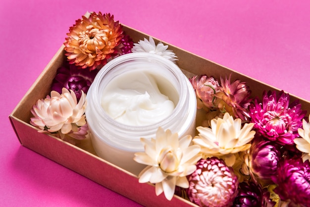 Crema cosmética en mesa rosa