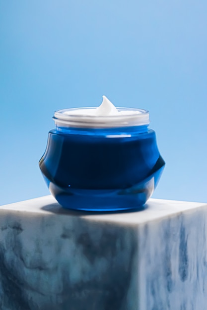 Crema facial de belleza cosmética y cuidado de la piel antienvejecimiento en tarro sobre fondo azul