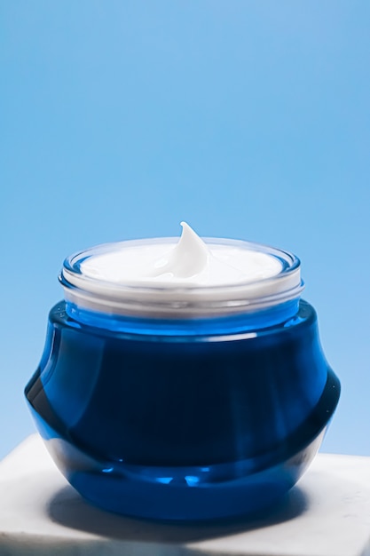 Crema facial de belleza cosmética y cuidado de la piel antienvejecimiento en tarro sobre fondo azul