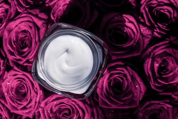 Crema facial hidratante para la piel en rosas rosadas flores producto cosmético de lujo para el cuidado de la piel sobre fondo floral como marca de belleza diseño plano de vacaciones