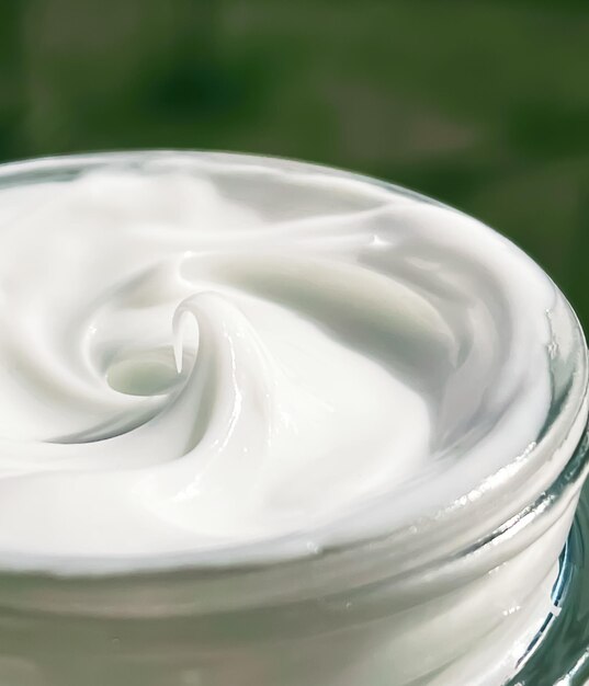 Crema facial hidratante tarro de vidrio en la naturaleza cuidado de la piel y concepto de producto de belleza orgánico verde cosmético