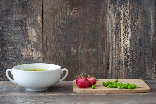 Crema de guisantes con rábanos en una mesa de madera rústica