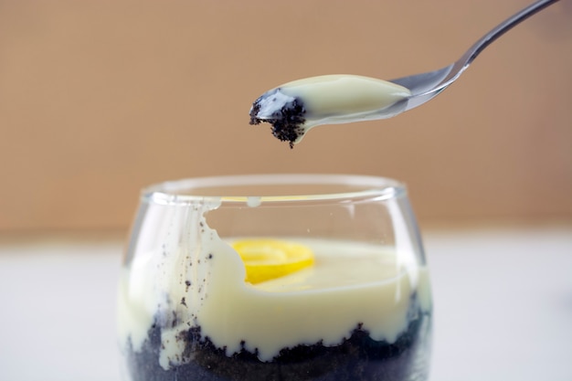 Foto crema de limón siciliano y galletas verrine con cuchara sobre fondo marrón