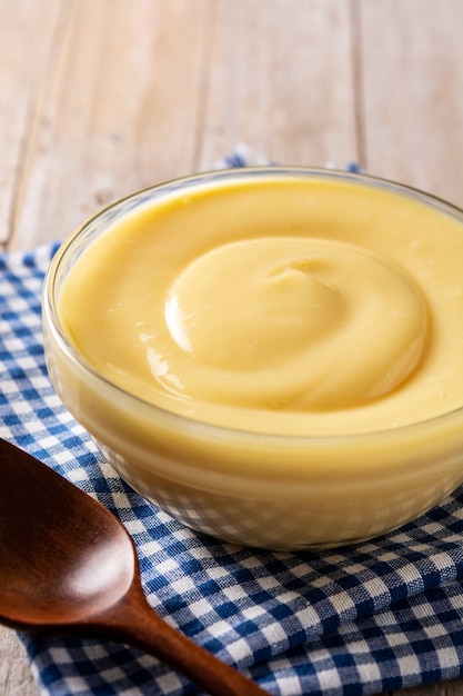 Foto crema pastelera en un recipiente sobre la mesa de madera