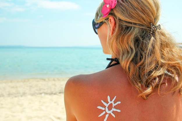 Crema solar en la espalda femenina en la playa