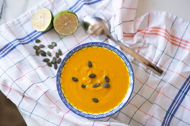 Crema-sopa de calabaza con limón y semillas en un tazón con una cuchara. Concepto de comida casera saludable