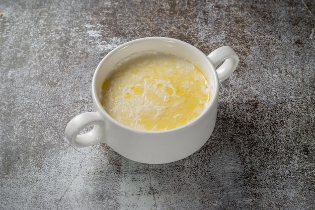 Crema de trigo, pudín de sémola con mantequilla en una taza blanca contra una mesa de piedra gris. Un desayuno saludable en un restaurante.