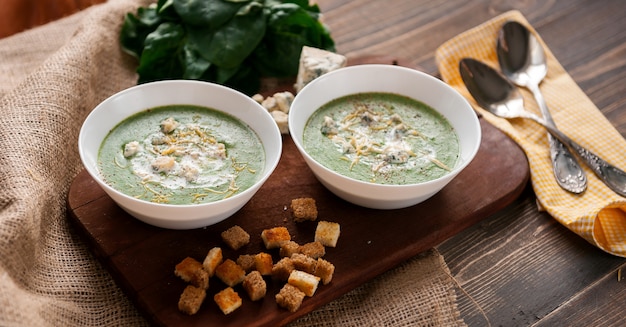 Crema verde de espinacas y brócoli. con la adición de parmesano y queso azul con picatostes. Una superficie de madera.