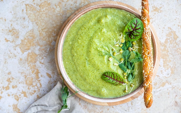 Foto crema de verduras verdes con micro verduras y palitos de pan sopa vegana puré de verduras verdes