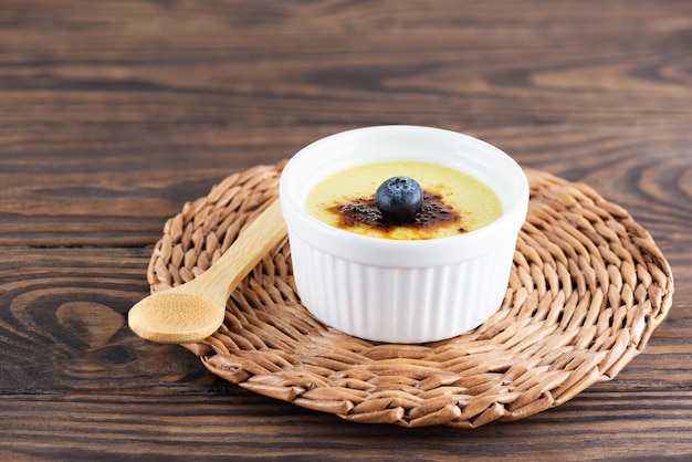 Creme brulée casero con arándanos en un bol sobre una mesa de madera