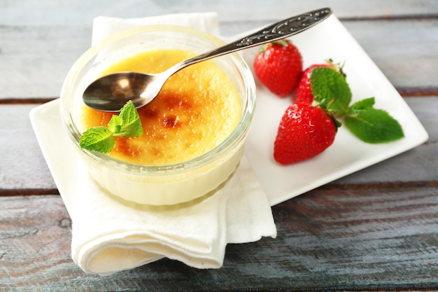 Foto creme brulee dessert auf serviette auf farbigem holzhintergrund