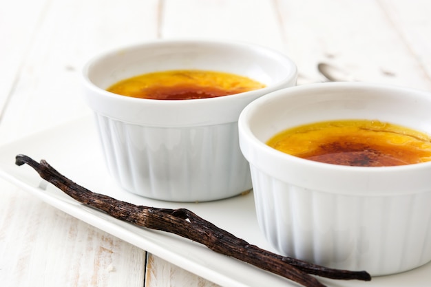 Creme brulee e vagem de baunilha na mesa de madeira branca