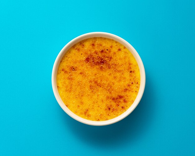 Crème Brûlée in Auflaufform isoliert auf hellem Blau