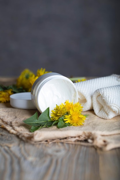 Creme com extrato de dente de leão em uma garrafa de plástico branca sobre uma superfície de madeira. Fechar-se