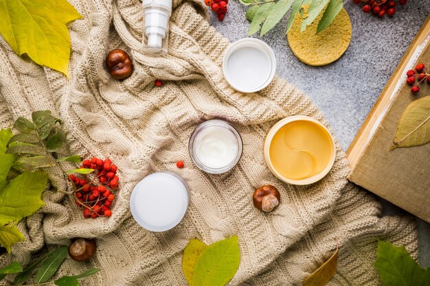 Creme cosmético antienvelhecimento e tapa-olhos no fundo do outono de folhas verdes e secas