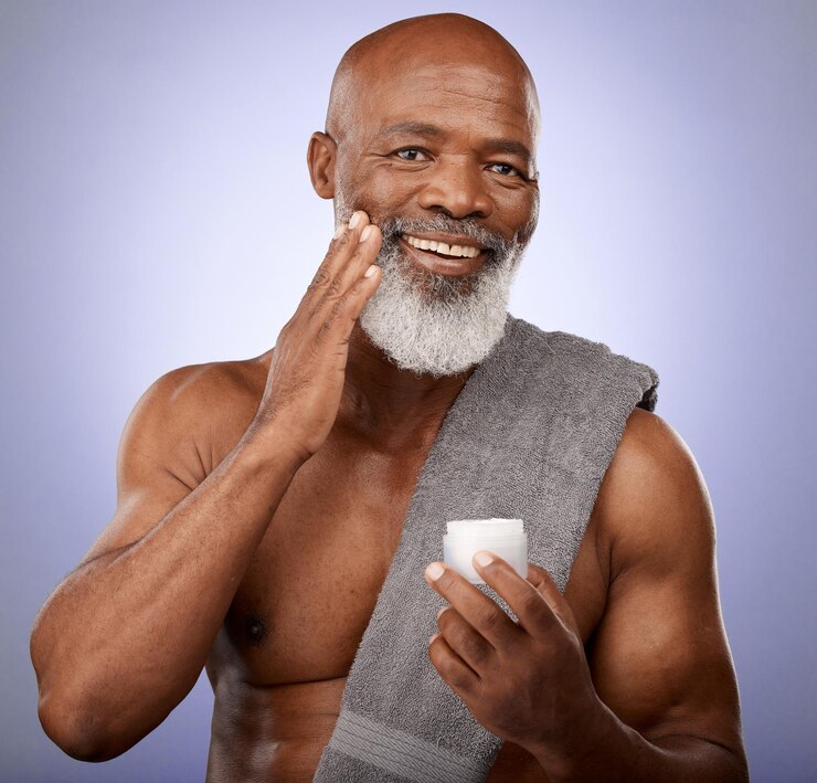 Foto creme de beleza para a pele e retrato de estúdio de homem negro com uma toalha e loção para produtos cosméticos de autocuidado e dermatologia em um fundo roxo rosto de homem negro com um sorriso para uma pele saudável