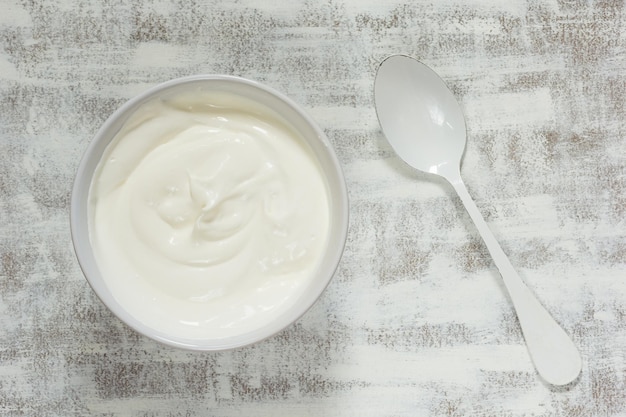 Foto creme de leite em tigela branca com colher branca no fundo branco