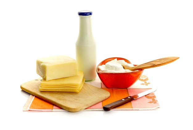 Creme de leite em uma tigela de queijo e leite em uma garrafa em um fundo branco closeup